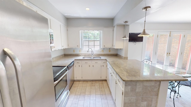 kitchen featuring white cabinets, appliances with stainless steel finishes, a sink, a breakfast bar area, and a peninsula