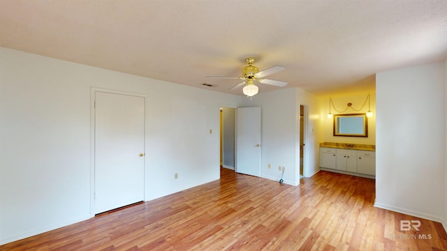 unfurnished bedroom featuring a ceiling fan, visible vents, baseboards, connected bathroom, and light wood-style flooring