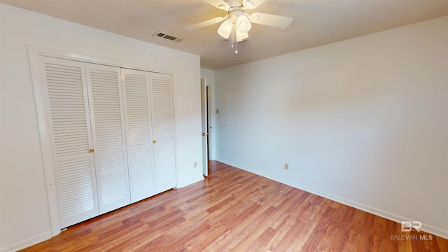 unfurnished bedroom featuring ceiling fan, visible vents, baseboards, a closet, and light wood-style floors