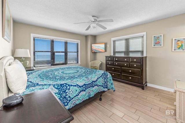 bedroom featuring light hardwood / wood-style floors, ceiling fan, and a textured ceiling