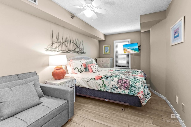 bedroom with light hardwood / wood-style floors, ceiling fan, and a textured ceiling