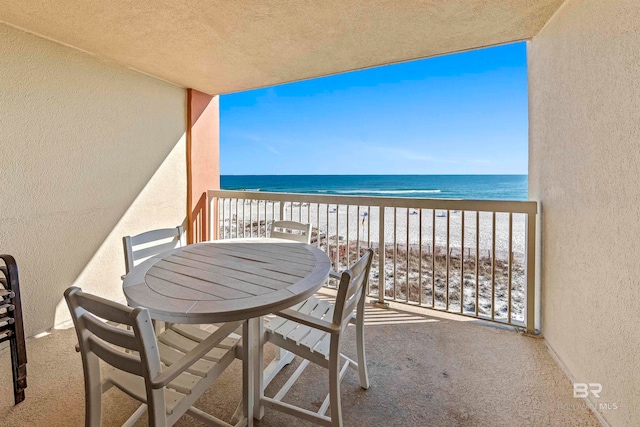 balcony with a water view and a view of the beach