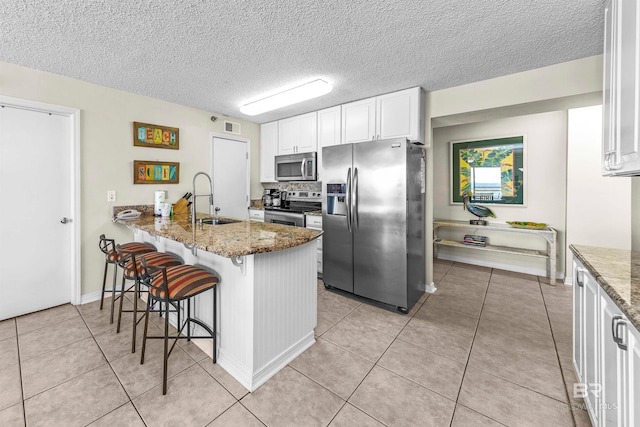 kitchen featuring dark stone counters, stainless steel appliances, a kitchen bar, and sink