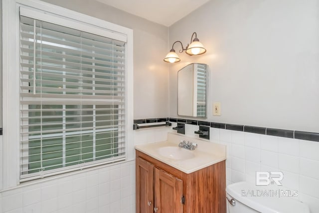 bathroom with vanity, toilet, and tile walls