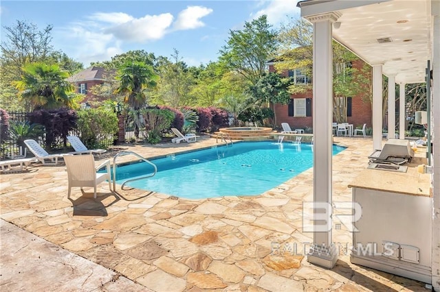 view of swimming pool with a patio area, pool water feature, and an in ground hot tub