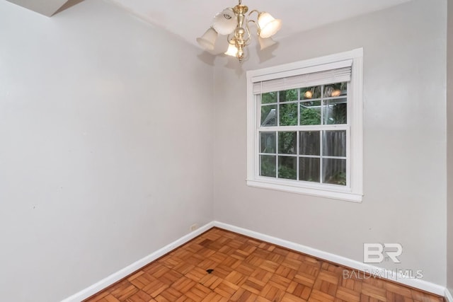 empty room featuring light parquet flooring and a chandelier