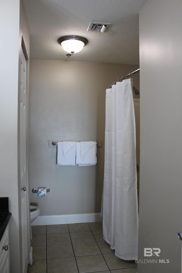 bathroom with vanity, a textured ceiling, toilet, and tile patterned floors