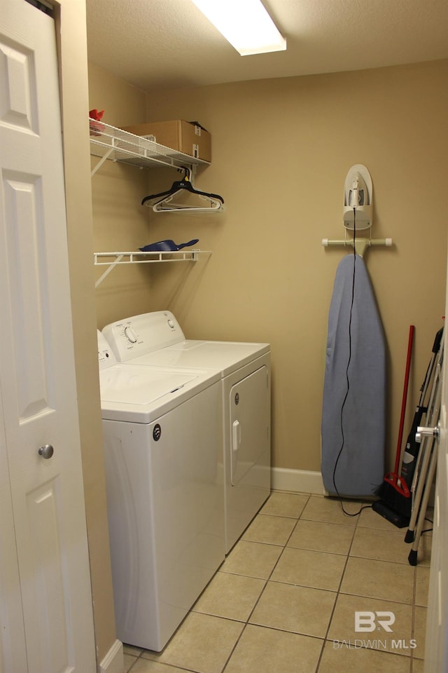 laundry area with a textured ceiling, separate washer and dryer, and light tile patterned floors