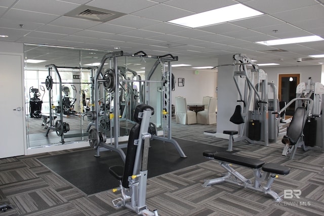 workout area featuring a drop ceiling and dark colored carpet