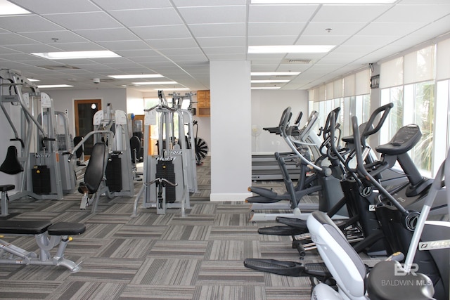 exercise room featuring a drop ceiling and dark colored carpet