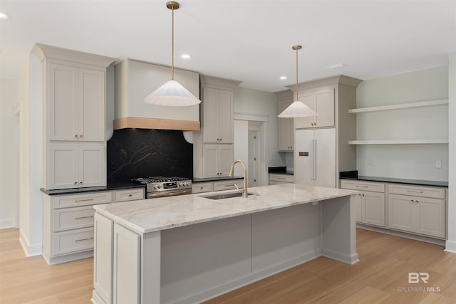 kitchen featuring stainless steel gas range oven, sink, hanging light fixtures, and white refrigerator with ice dispenser