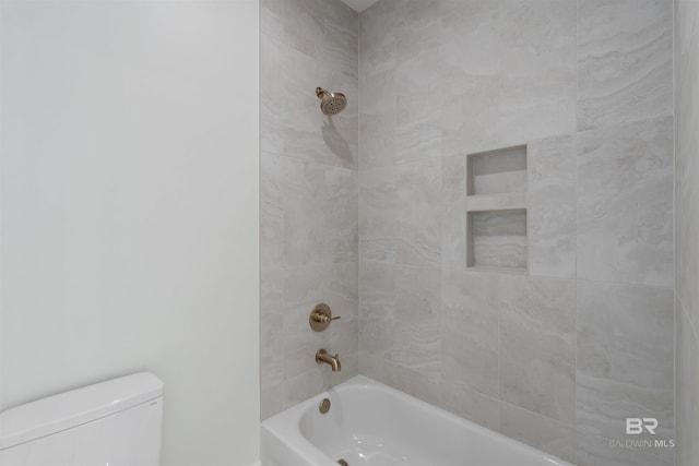 bathroom featuring tiled shower / bath and toilet