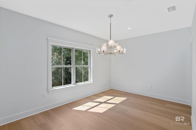 spare room with light hardwood / wood-style floors and a chandelier