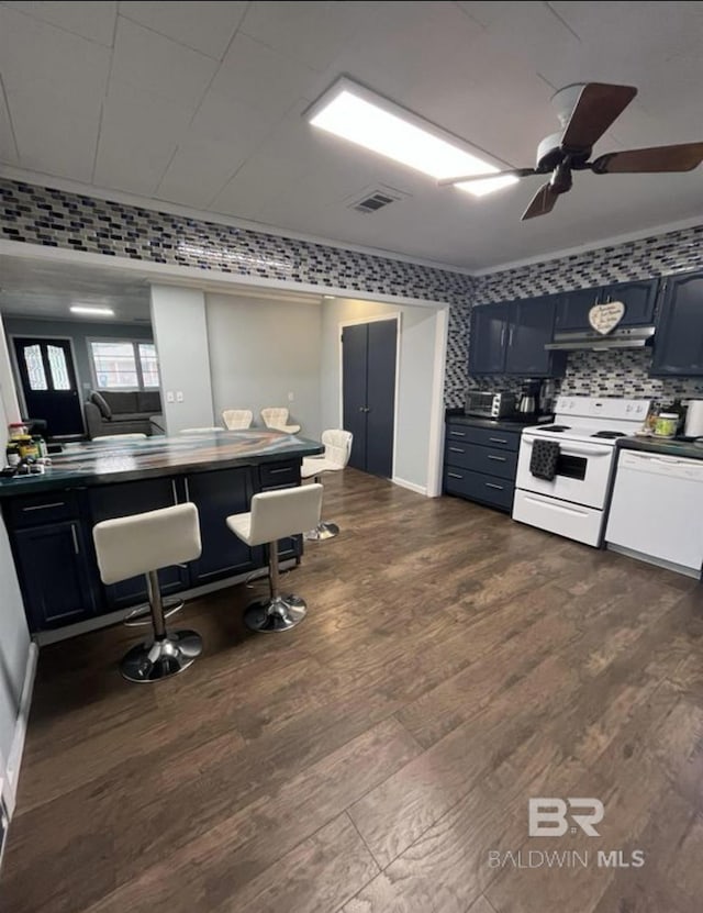 kitchen with dark wood-type flooring, white appliances, blue cabinetry, and tasteful backsplash