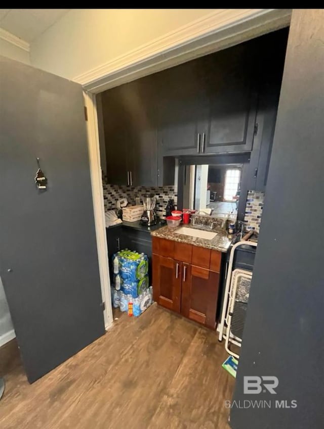 kitchen featuring hardwood / wood-style flooring, light stone countertops, sink, and decorative backsplash