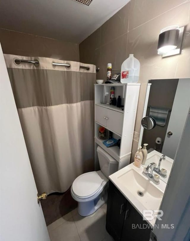 bathroom with tile walls, vanity, toilet, tile patterned floors, and a shower with shower curtain