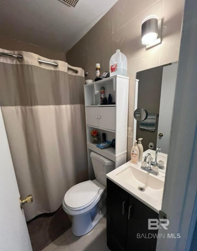 bathroom with vanity, toilet, a shower with shower curtain, and tile walls