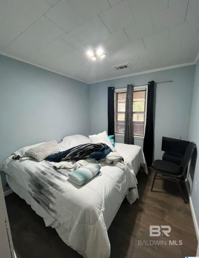 bedroom with ornamental molding and dark hardwood / wood-style floors