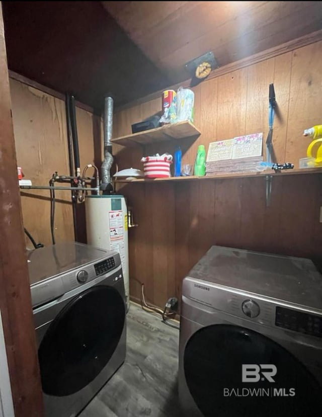 laundry area with gas water heater, independent washer and dryer, and wood walls