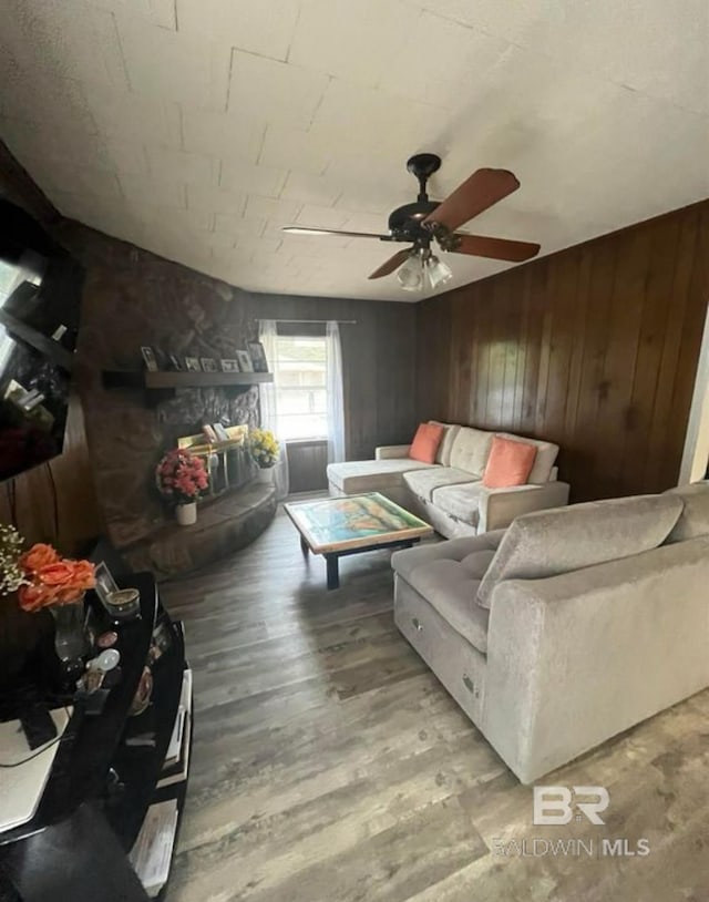 living room featuring ceiling fan, light hardwood / wood-style floors, and wood walls