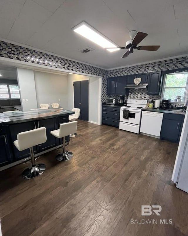 kitchen with white appliances, blue cabinetry, ceiling fan, dark hardwood / wood-style floors, and decorative backsplash