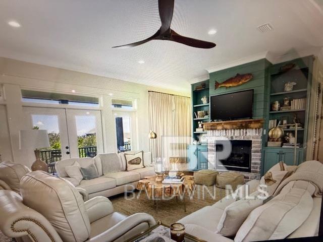 living area featuring built in shelves, a ceiling fan, visible vents, french doors, and a brick fireplace