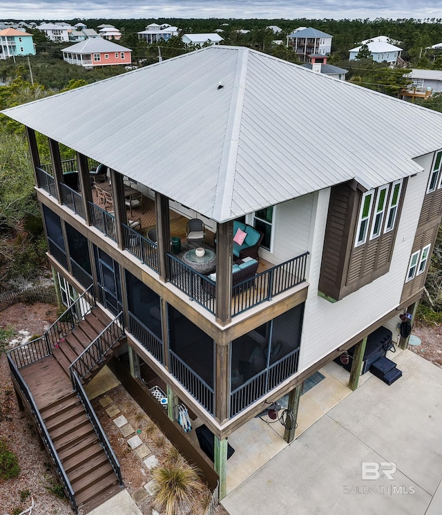 back of house featuring a patio area, stairway, and metal roof