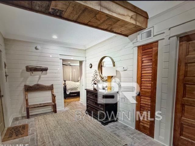 interior space featuring visible vents, wood walls, and brick floor