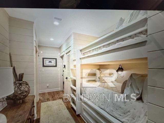 bedroom with wooden walls, recessed lighting, and wood finished floors