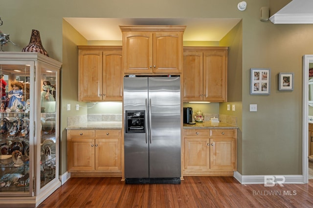 kitchen featuring light stone countertops, ornamental molding, dark wood-type flooring, and stainless steel fridge with ice dispenser