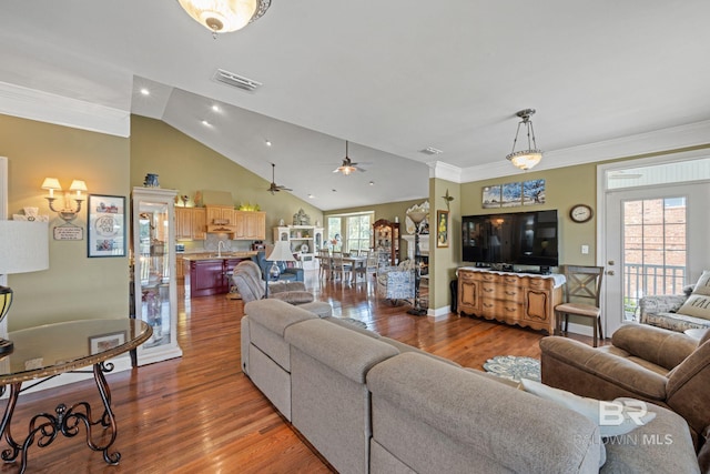 living room with wood-type flooring, lofted ceiling, crown molding, and ceiling fan