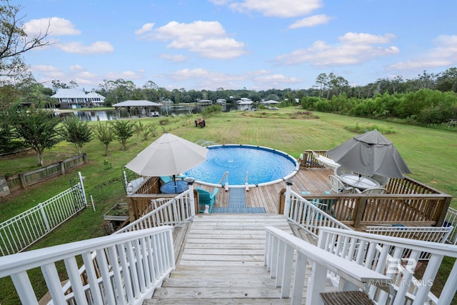 view of pool with a lawn and a deck with water view