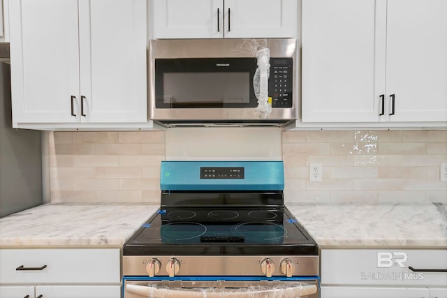 kitchen with white cabinetry, light stone countertops, appliances with stainless steel finishes, and decorative backsplash