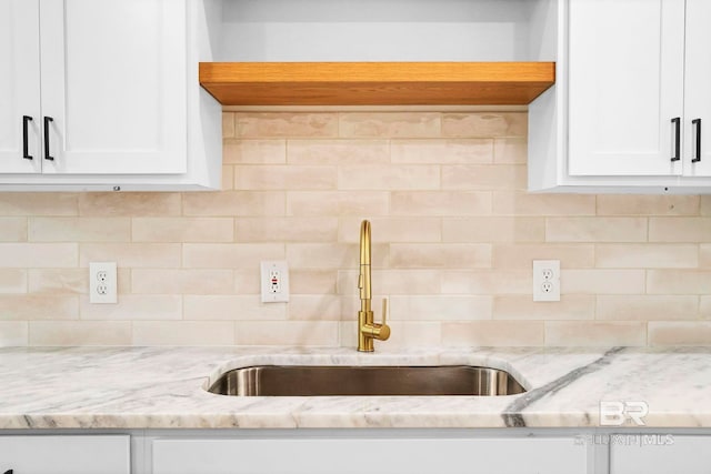 kitchen featuring white cabinetry, a sink, and backsplash