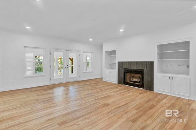 unfurnished living room with built in shelves, french doors, and plenty of natural light