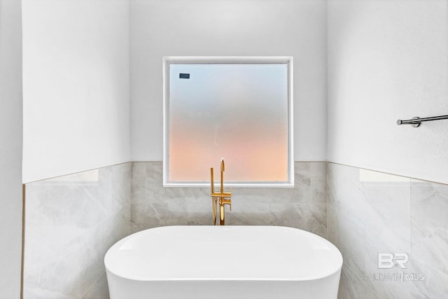 bathroom featuring a soaking tub and wainscoting