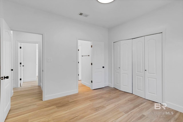 unfurnished bedroom featuring baseboards, visible vents, a closet, and light wood-style floors