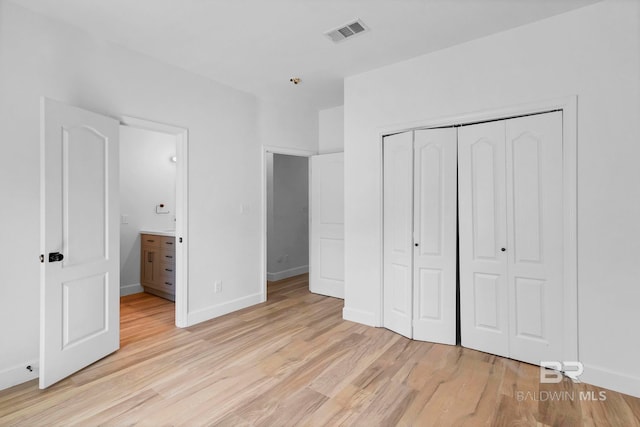unfurnished bedroom with baseboards, visible vents, a closet, and light wood-type flooring