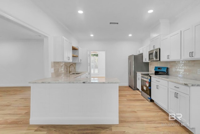 kitchen with a sink, open shelves, light wood-style flooring, stainless steel appliances, and visible vents