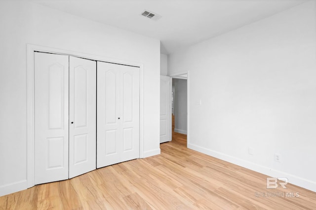 unfurnished bedroom with light wood-style flooring, baseboards, a closet, and visible vents