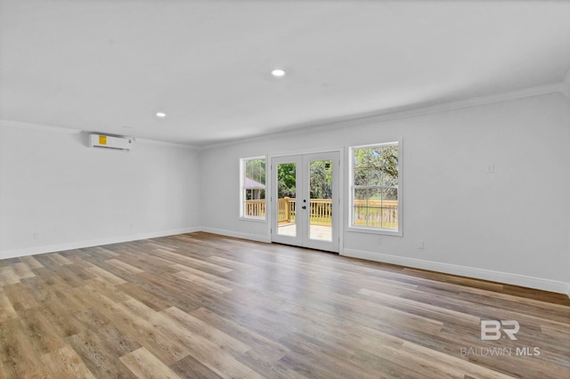 spare room with french doors, wood finished floors, a wall mounted air conditioner, baseboards, and ornamental molding