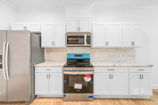 kitchen featuring white cabinets, stainless steel appliances, and crown molding