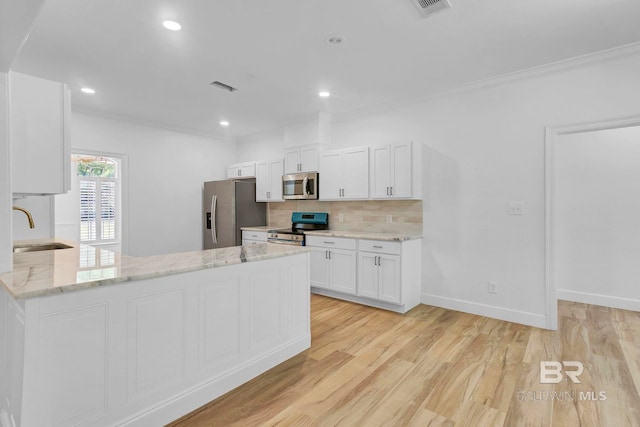 kitchen featuring tasteful backsplash, stainless steel appliances, a sink, light wood-style floors, and visible vents