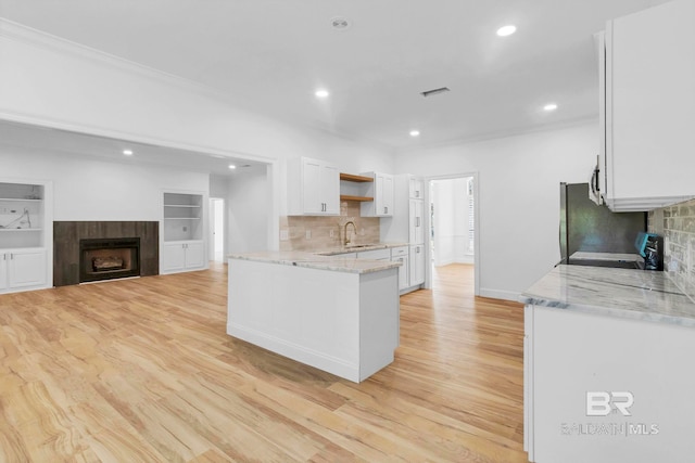 kitchen featuring white cabinetry, range, visible vents, light wood-style flooring, and a tile fireplace