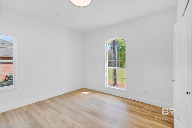 spare room with baseboards and light wood-style flooring