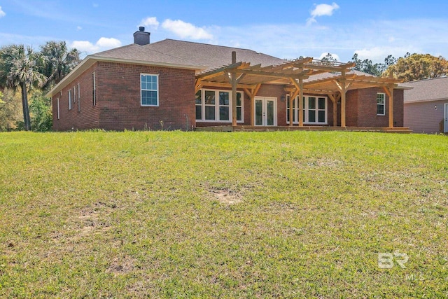 rear view of house featuring french doors, brick siding, a pergola, a yard, and a chimney