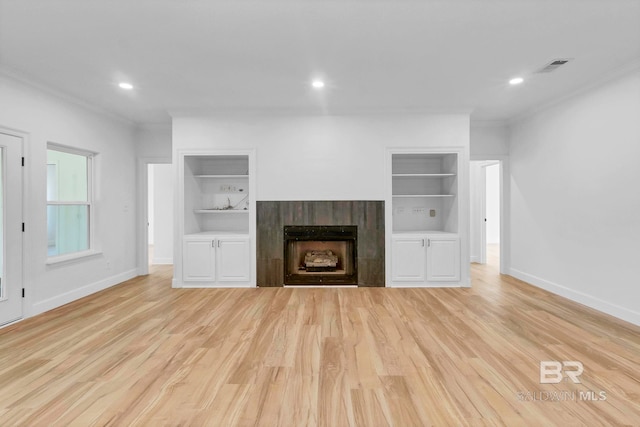 unfurnished living room featuring light wood finished floors, baseboards, visible vents, and built in shelves