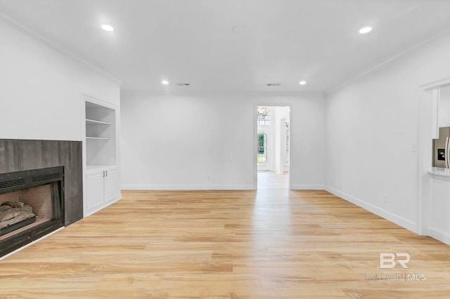 unfurnished living room with light wood-style flooring, built in features, a fireplace, and crown molding