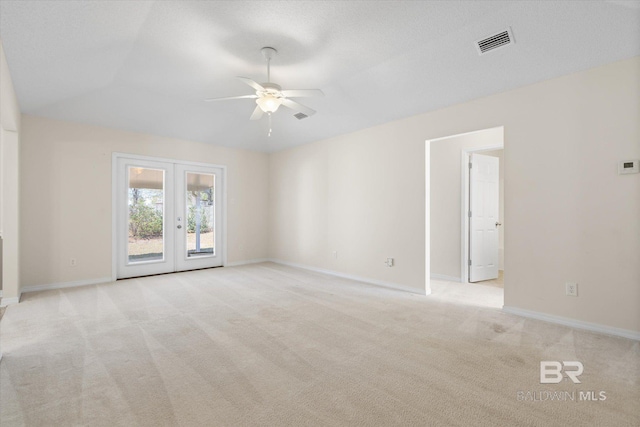 spare room with visible vents, a ceiling fan, french doors, light colored carpet, and vaulted ceiling