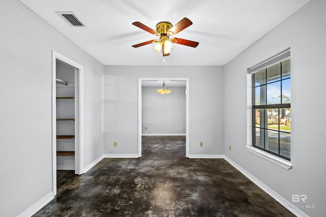 unfurnished room featuring plenty of natural light, ceiling fan with notable chandelier, and a textured ceiling